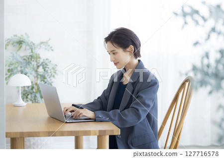 Woman working on a computer in the living room 127716578