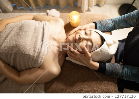 Woman receiving a head massage Woman receiving a head massage 127717120
