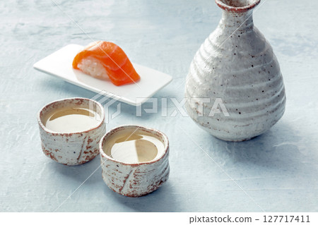 Sake in a pitcher and ochoko, traditional cup, with salmon nigiri Sake in a pitcher and ochoko, traditional cup, with salmon nigiri 127717411