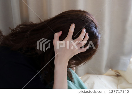 A woman holding her head worried image 127717540
