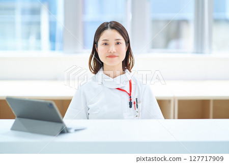 A woman in a white coat sitting at a table 127717909