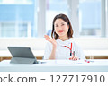 A woman in a white coat sitting at a table 127717910