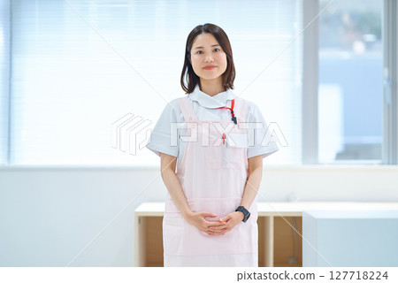 A woman in a white coat and apron 127718224