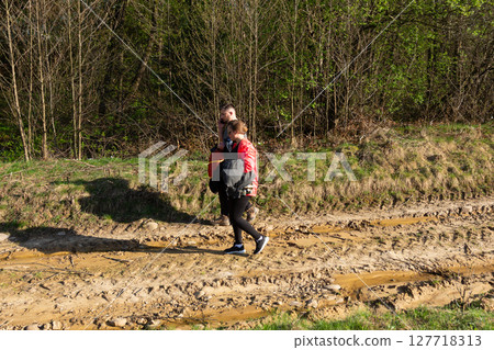 Couple enjoying a peaceful walk through the lush green forest path on a sunny spring day, embracing nature and each other's company amidst the tranquil scenery 127718313