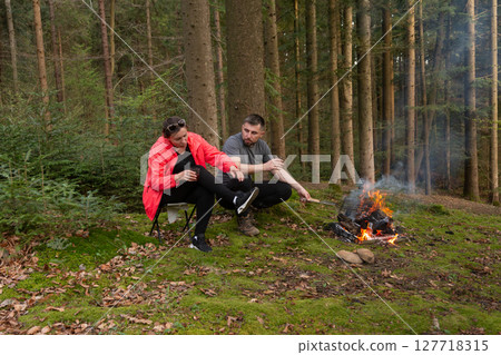 Cozy moments by the fire in the serene woods during an autumn afternoon, sharing stories and savoring the warmth of nature 127718315