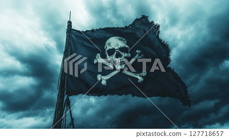 Tattered Jolly Roger pirate flag waving against stormy turquoise sky. Dramatic black flag with white skull and crossbones symbolizes maritime history and adventure 127718657