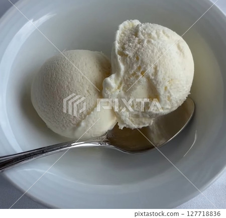 Delicious Vanilla Ice Cream Scoops in a White Bowl with Silver Spoon, on a soft fabric surface Delicious Vanilla Ice Cream Scoops in a White Bowl with Silver Spoon, on a soft fabric surface 127718836