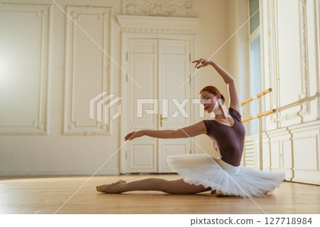 Young ballerina in tutu skirt stretching practicing ballet positions dancing in dance class. Young classical dancer woman in dance studio. Ballet class training Ballet school concept Young ballerina in tutu skirt stretching practicing ballet positions dancing in dance class. Young classical dancer woman in dance studio. Ballet class training Ballet school concept 127718984