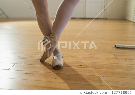Worn ballet pointe shoes on feet in dance class. Well worn pointe shoes of ballet dancer. Classical ballerina woman in dance studio. Classical pointe shoes for dance training. Ballet school concept 127718995