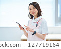A woman in a white coat and apron holding a smartphone 127719164