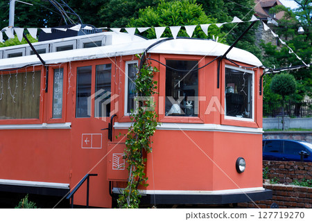 Charming Vintage Tram: A Beautifully Restored Transportation Museum Attraction with Unique Orange Color and Decorative Elements in a Picturesque Outdoor Setting Charming Vintage Tram: A Beautifully Restored Transportation Museum Attraction with Unique Orange Color and Decorative Elements in a Picturesque Outdoor Setting 127719270