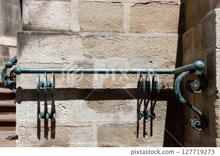 Intricate Ironwork: Decorative Handrail and its Unique Design Feature on Stone Wall Evokes Charm of Historical Architecture and Craftsmanship in Urban Settings 127719273