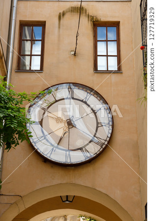 A Beautifully Designed Clock Graces the Wall of an Arched Passageway, Adding Character and Charm to Architecture with Its Vintage Style and Distinctive Artistic Elements 127719329