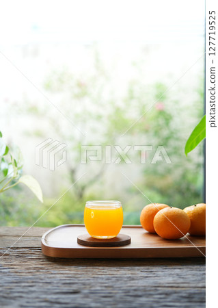 fresh oranges and orange juice on wooden tray by the window 127719525