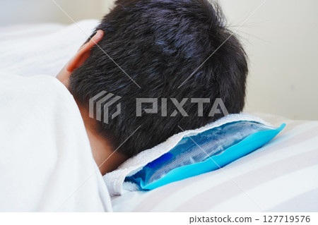 A young man resting in bed with an ice pack due to heatstroke caused by the extreme heat A young man resting in bed with an ice pack due to heatstroke caused by the extreme heat 127719576