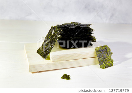 Crispy nori seaweed on white wooden background. Japanese dry seaweed sheets 127719779