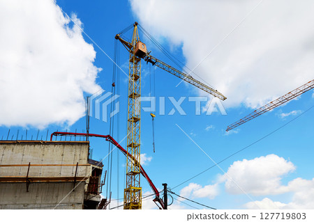 Cranes and other equipment on the construction site against the blue sky. Cranes and other equipment on the construction site against the blue sky. 127719803
