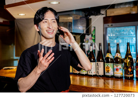Man talking on smartphone at a bar 127720073
