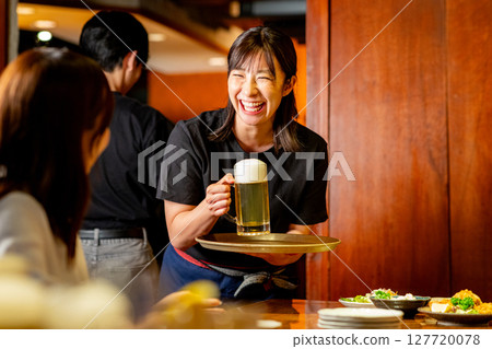 A woman serving customers at an izakaya 127720078