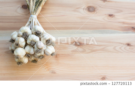 bunch of tied garlic on wooden background, spices, crop 127720113