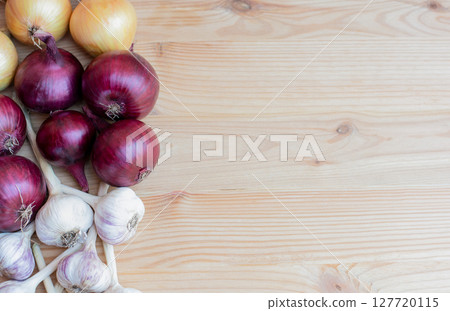 Red and yellow onions with garlic lie on a wooden background harvest. Copy space Red and yellow onions with garlic lie on a wooden background harvest. Copy space 127720115
