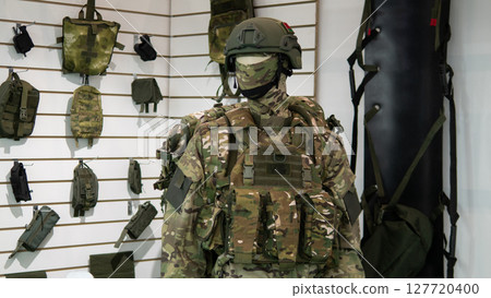 A soldier stands in an armory, fully equipped with tactical gear and weapons, emphasizing the preparation and seriousness of military operations in conflict situations. A soldier stands in an armory, fully equipped with tactical gear and weapons, emphasizing the preparation and seriousness of military operations in conflict situations. 127720400