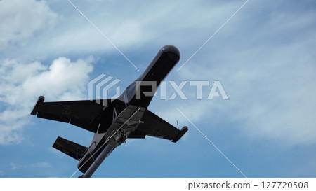 A military drone is seen soaring through the sky above a war-torn area, showcasing its surveillance and combat capabilities during ongoing military operations. 127720508