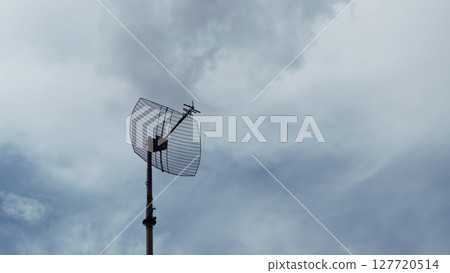 A tall surveillance tower equipped with antennas reaches towards the cloudy sky, observing an area affected by ongoing conflict and military activities. A tall surveillance tower equipped with antennas reaches towards the cloudy sky, observing an area affected by ongoing conflict and military activities. 127720514