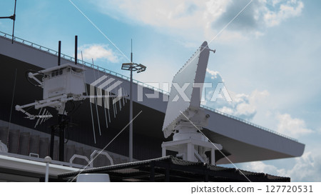 High-tech military gear is positioned atop a warship, showcasing surveillance capabilities in a coastal environment during military operations. 127720531