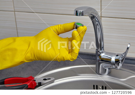 replacing the mixer aerator in a metal sink. work on house replacing the mixer aerator in a metal sink. work on house 127720596