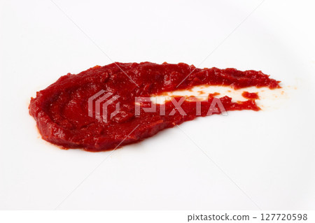 red blob of tomato ketchup paste smeared on white table. isolated on white background 127720598