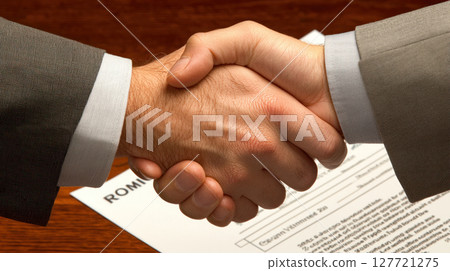 close up of hands shaking over contract for financial services, symbolizing agreement and partnership close up of hands shaking over contract for financial services, symbolizing agreement and partnership 127721275