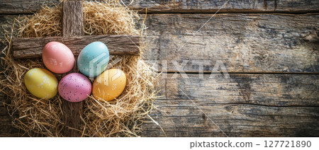 Easter eggs nestled in straw with wooden cross background create vintage style. Perfect for seasonal celebrations 127721890