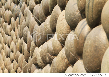 Round stone wall on a bright sunny day. 127722264