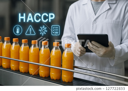Juice production line monitored by food safety specialist with tablet applying HACCP principles to track contamination risks and ensure compliance 127722833