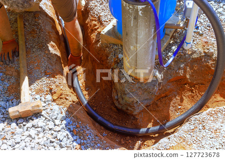 Workers are installing water laying pipe at construction site, digging in ground under works day Workers are installing water laying pipe at construction site, digging in ground under works day 127723678
