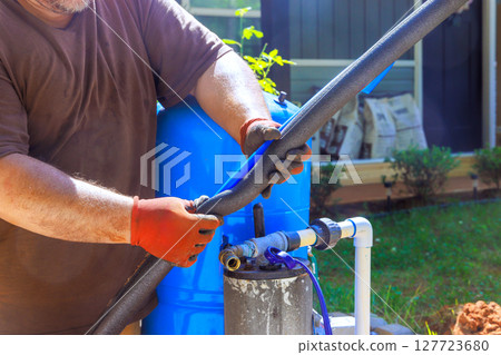 Contractor installs hoses connect to water well fittings on an irrigation system in backyard works day. 127723680