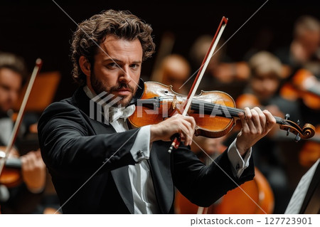Violinist performs passionately in concert hall with orchestra at evening event showcasing musical talent and emotional artistry 127723901