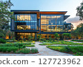 Modern architectural building surrounded by lush landscaping in a serene outdoor setting during late afternoon sunlight 127723962