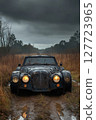Abandoned vintage car resting on a muddy track in a foggy forest landscape during overcast weather in the late afternoon 127723965