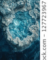Unique rock formation surrounded by turquoise ocean waters viewed from above during bright daylight in a coastal region 127723967