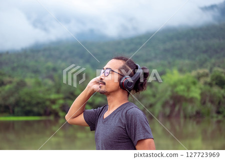 Man enjoying music in nature with serene view. 127723969