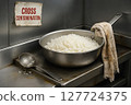 Cross Contamination hazard in foodservice line with stained kitchen cloth in direct contact with hot rice in saute pan, violating hygiene protocols in industrial environment 127724375