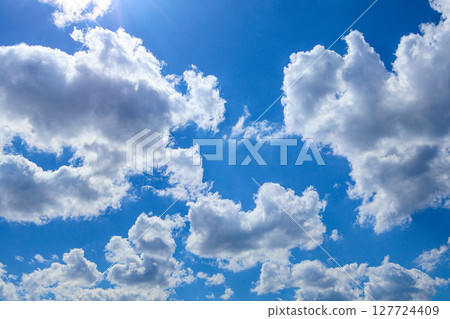 Expansive bright blue sky adorned with fluffy white cumulus clouds, signifying a clear sunny day ideal for outdoor freedom and natural beauty 127724409