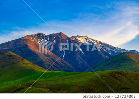 Majestic mountain range with snow-capped peaks and green hills in Kyrgyzstan Majestic mountain range with snow-capped peaks and green hills in Kyrgyzstan 127724802