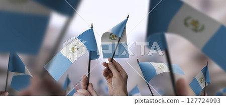 Guatemala flags in their hands on a blurred urban background 127724993