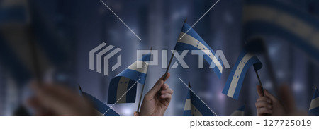 Honduras flags in their hands on a blurred urban background 127725019