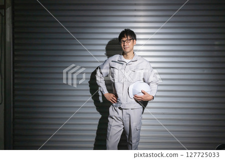 Man in work clothes holding a helmet 127725033