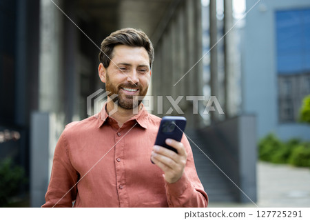 Successful man with phone in hands close up, employee browsing social networks and typing text message. Businessman using app to analyze financial indicators. Successful man with phone in hands close up, employee browsing social networks and typing text message. Businessman using app to analyze financial indicators. 127725291