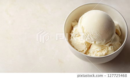 Vanilla ice cream scoops in a white bowl on a light marble background. Creamy and cold dessert with smooth texture. Minimal sweet treat. 127725468